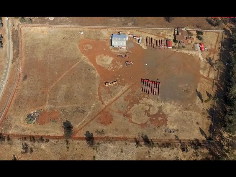 Aerial view of a large industrial plot featuring a central shed, perimeter fencing, and extensive open land area.
