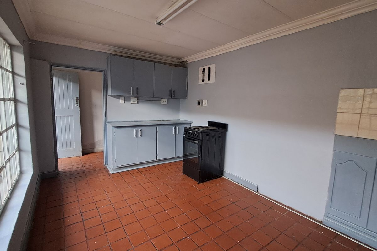 A functional kitchen space featuring built-in cabinetry, a freestanding stove, and tiled flooring, offering a blank canvas for potential renovation and modernization.