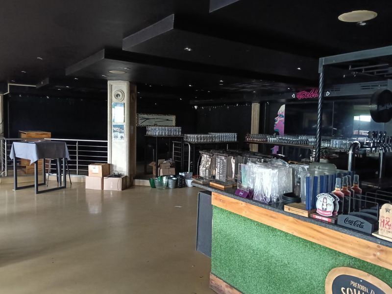 A spacious restaurant bar area featuring a built-in service counter, recessed ceiling lighting, and a modern open-plan layout.