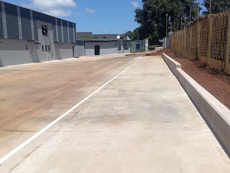 Spacious industrial yard area featuring concrete paving, perimeter walling with security fencing, and access to warehouse units.