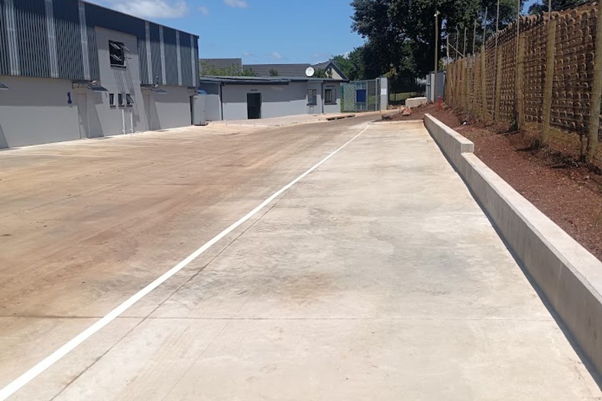 Spacious industrial yard area featuring concrete paving, perimeter walling with security fencing, and access to warehouse units.