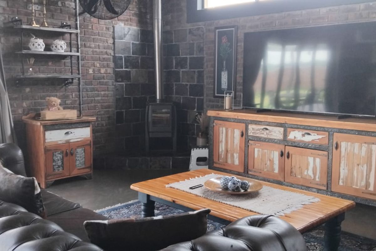 A cozy living room featuring exposed brick walls, a modern wood-burning fireplace, and polished concrete floors with access to the outdoors via sliding doors.