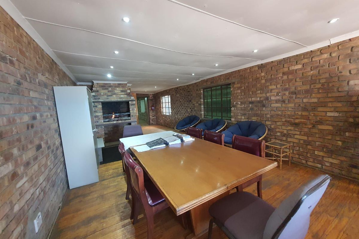 Spacious open plan area featuring exposed brick walls, wooden flooring, recessed ceiling lighting, and a built-in indoor fireplace.