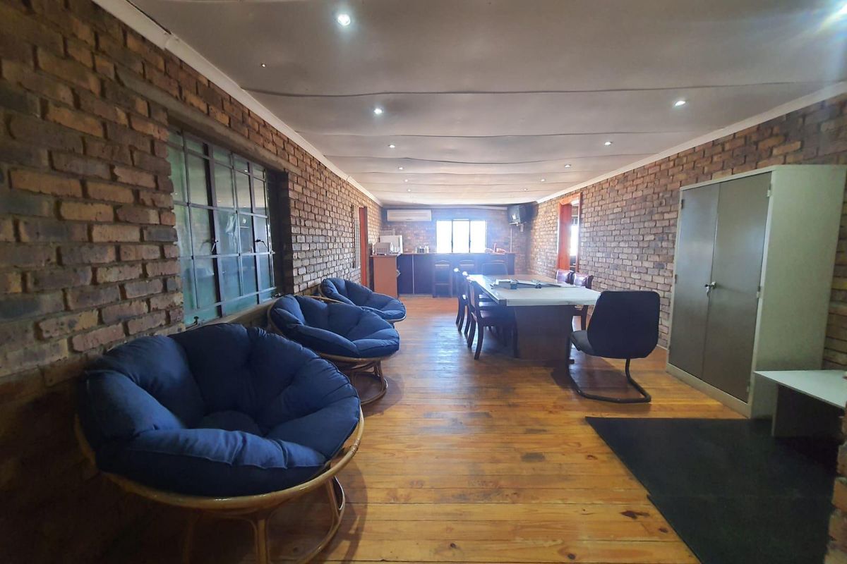 Spacious open-plan office or meeting area featuring exposed brick walls, timber flooring, recessed downlighting, and a built-in kitchenette counter.