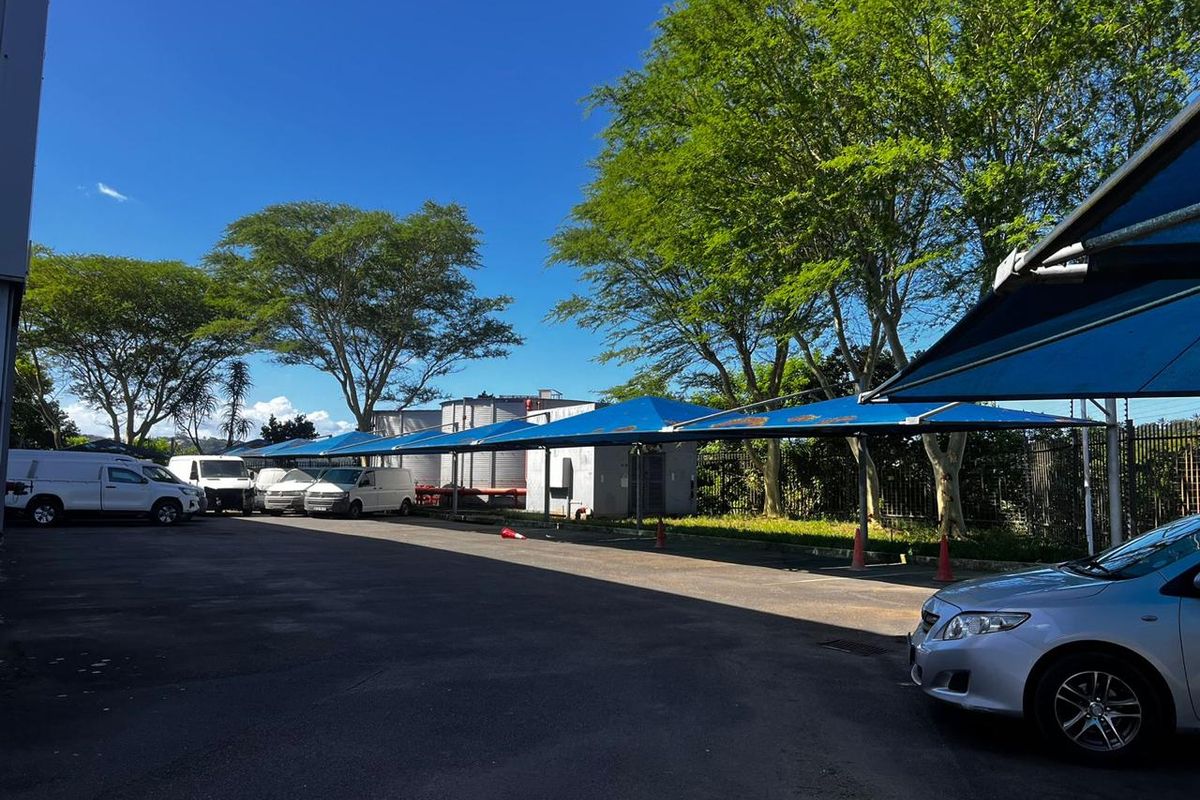 Industrial exterior parking area featuring extensive shade-net carports and paved driveway space.