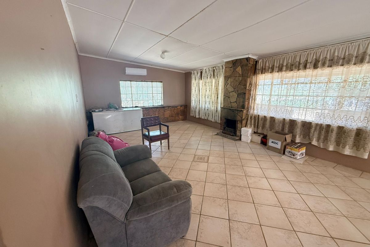Spacious living area featuring a stone-clad fireplace, tiled flooring, and a wall-mounted air conditioning unit.