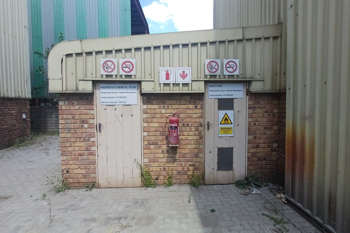 Industrial storage facility featuring dedicated hazardous chemical and gas storage units with external signage, fire safety equipment, and brick masonry construction.