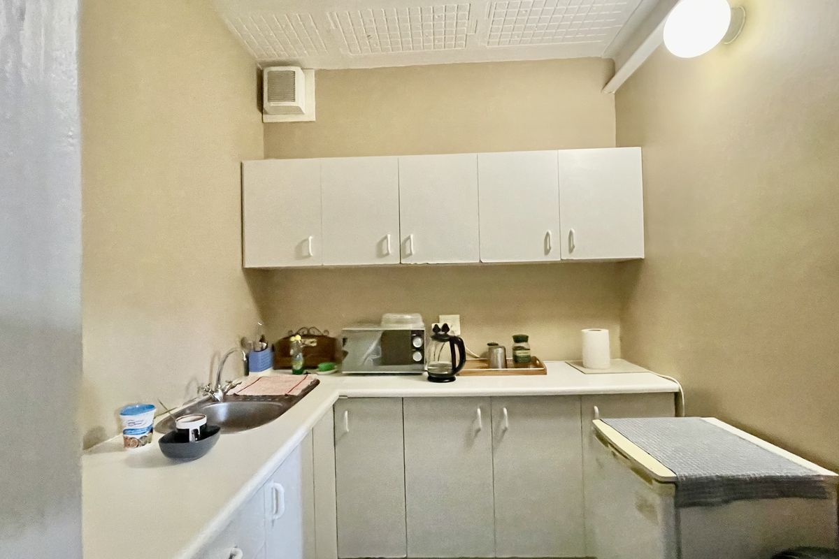 A compact office kitchenette featuring built-in cabinetry, a stainless steel sink, and laminate countertops, providing essential utility for a professional workspace.