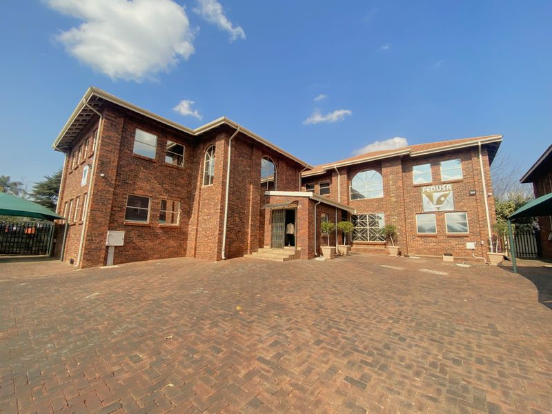 A well-maintained commercial building featuring a classic face-brick facade, paved courtyard, and large arched windows, providing a professional and welcoming entrance.