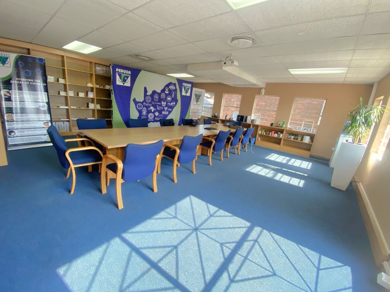 A functional commercial boardroom featuring built-in wooden shelving units, large windows for natural light, and a suspended ceiling grid.