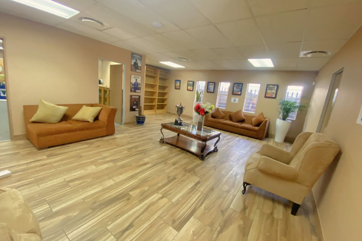 Spacious commercial waiting area featuring wood-look tile flooring, recessed ceiling lighting, and built-in shelving units.