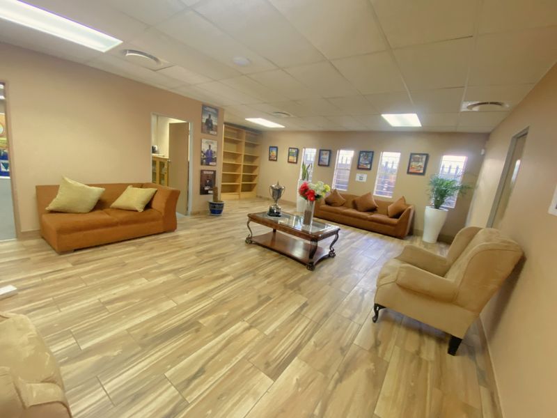 Spacious commercial waiting area featuring wood-look tile flooring, recessed ceiling lighting, and built-in shelving units.