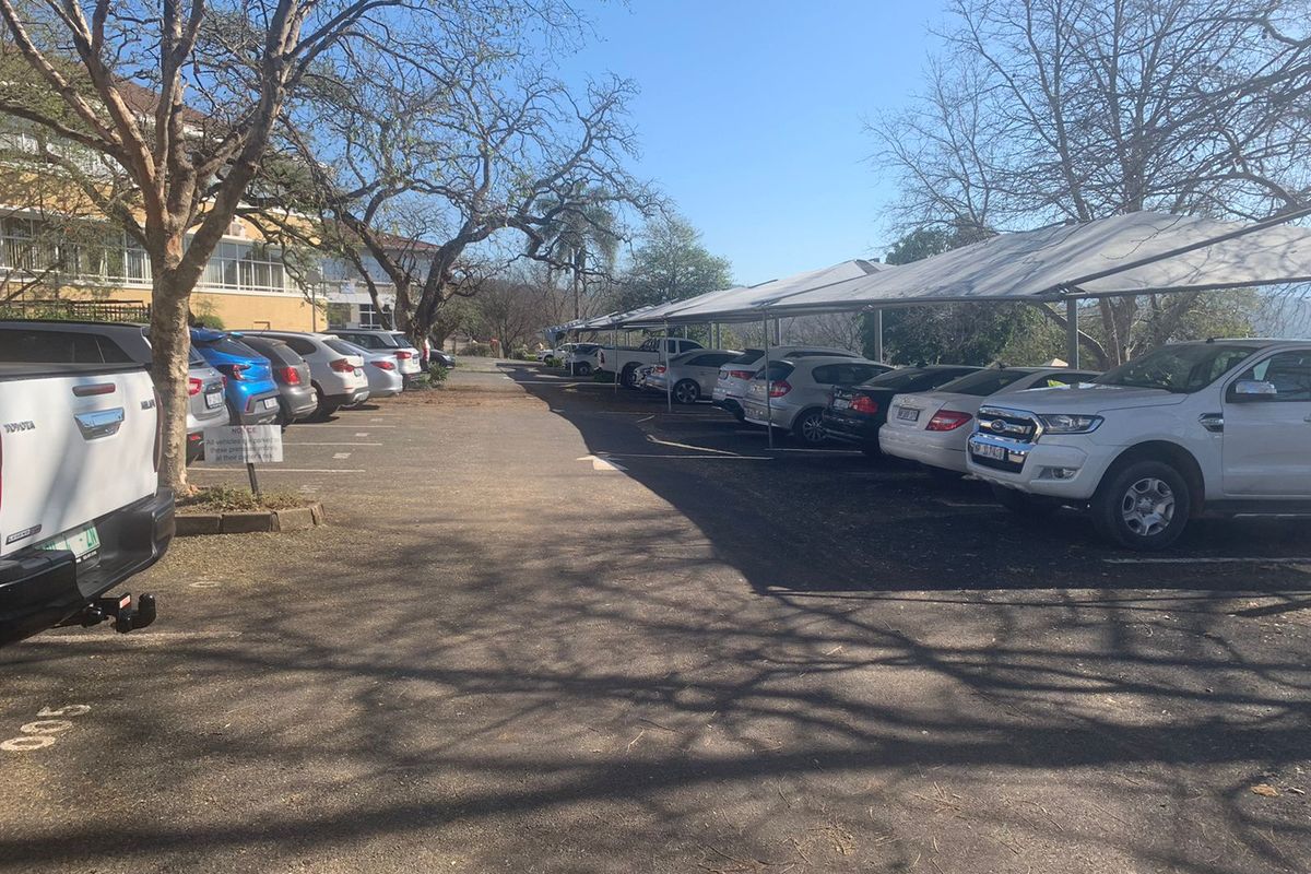 Outdoor parking area featuring asphalt surfacing and multiple shade cloth carports for vehicle protection.
