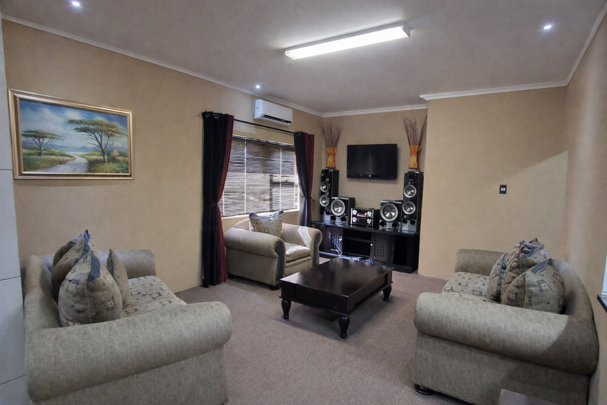 A comfortable living room featuring carpeted flooring, air conditioning, and venetian blinds, providing a functional space for relaxation.