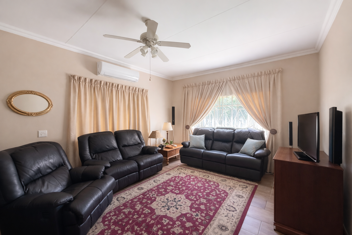 A comfortable living room featuring tiled flooring, a ceiling fan, and a wall-mounted air conditioning unit, with security bars installed on the window.