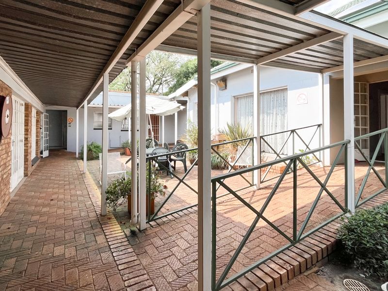 A covered outdoor patio area featuring brick paving, a metal roof structure, and a wheelchair-accessible ramp with metal railings.