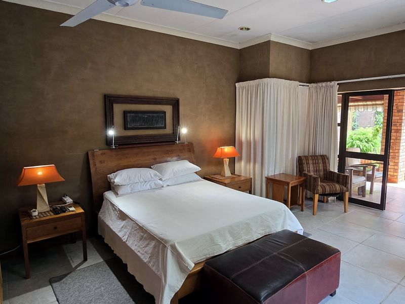 Spacious bedroom featuring tiled flooring, a ceiling fan, and direct access to an outdoor patio through sliding glass doors.