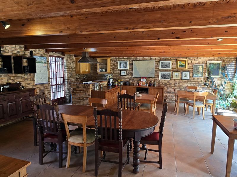 Spacious open-plan living and dining area featuring rustic face brick walls, exposed timber ceiling beams, and large glass doors providing ample natural light.