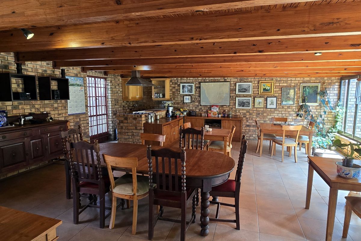 Spacious open-plan living and dining area featuring rustic face brick walls, exposed timber ceiling beams, and large glass doors providing ample natural light.