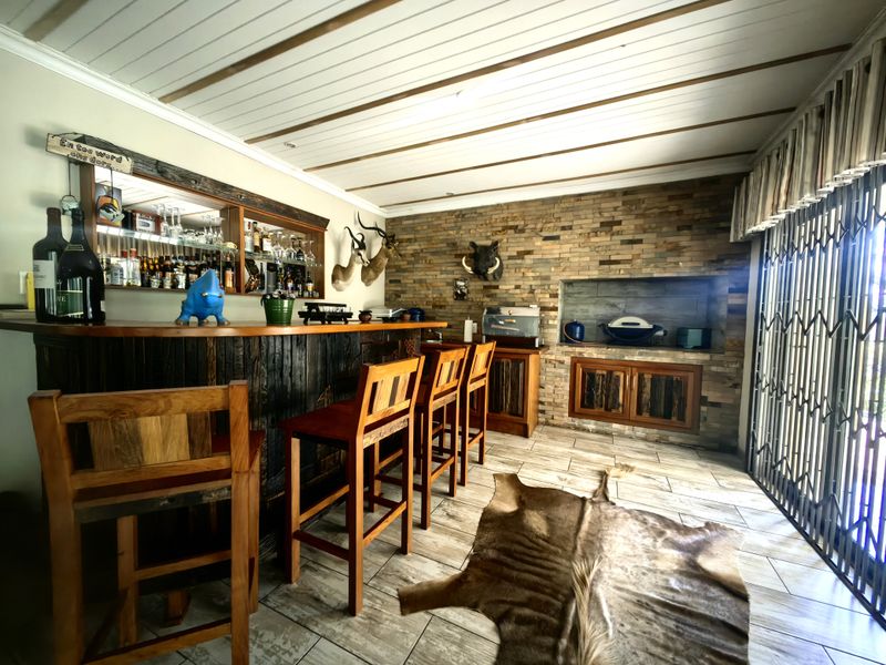 A rustic-style indoor bar area featuring a stone feature wall, built-in bar counter, timber ceiling, and secure access to the exterior.