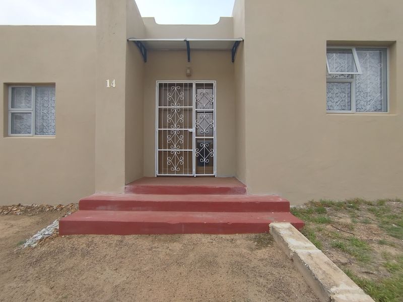 Front entrance of the property featuring a security gate, protective awning, and concrete steps leading to the main door.