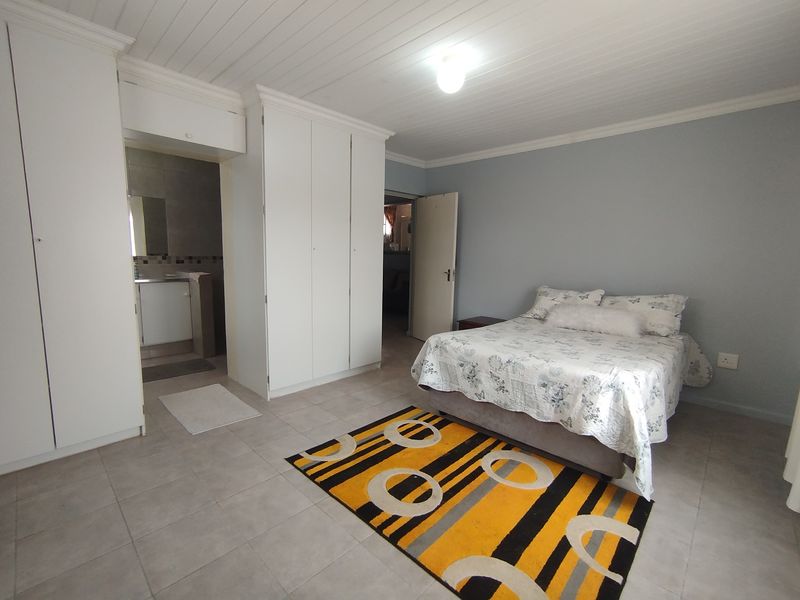 Spacious bedroom featuring built-in cupboards, tiled flooring, and a tongue and groove ceiling, with convenient access to an en-suite bathroom.