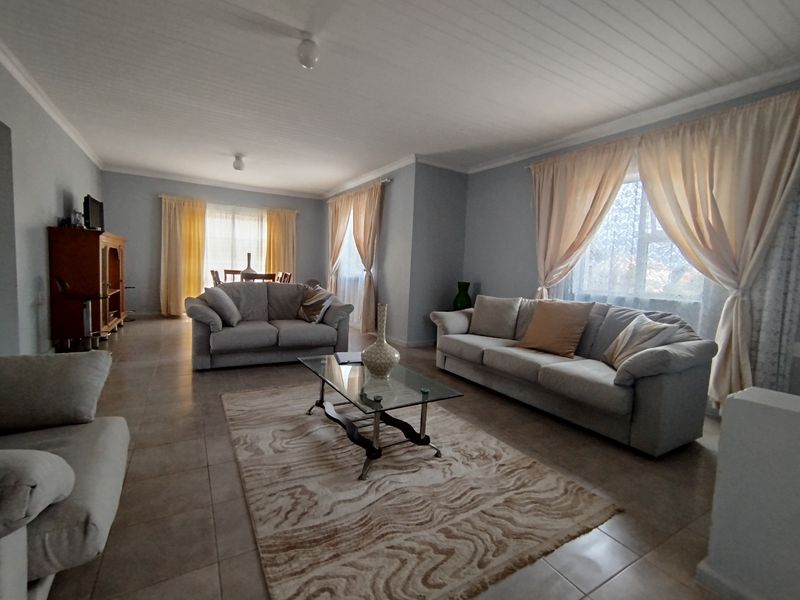Spacious living area featuring neutral tiled flooring and a classic tongue and groove ceiling, offering a bright and comfortable atmosphere.