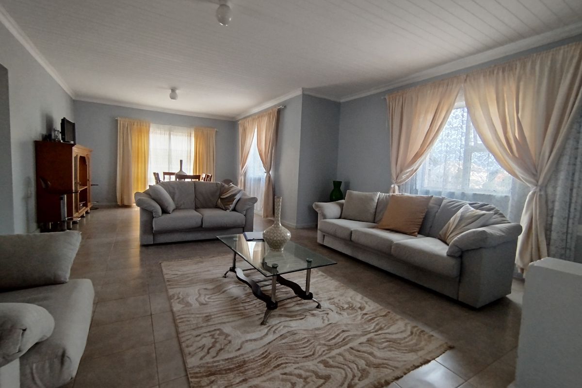 Spacious living area featuring neutral tiled flooring and a classic tongue and groove ceiling, offering a bright and comfortable atmosphere.