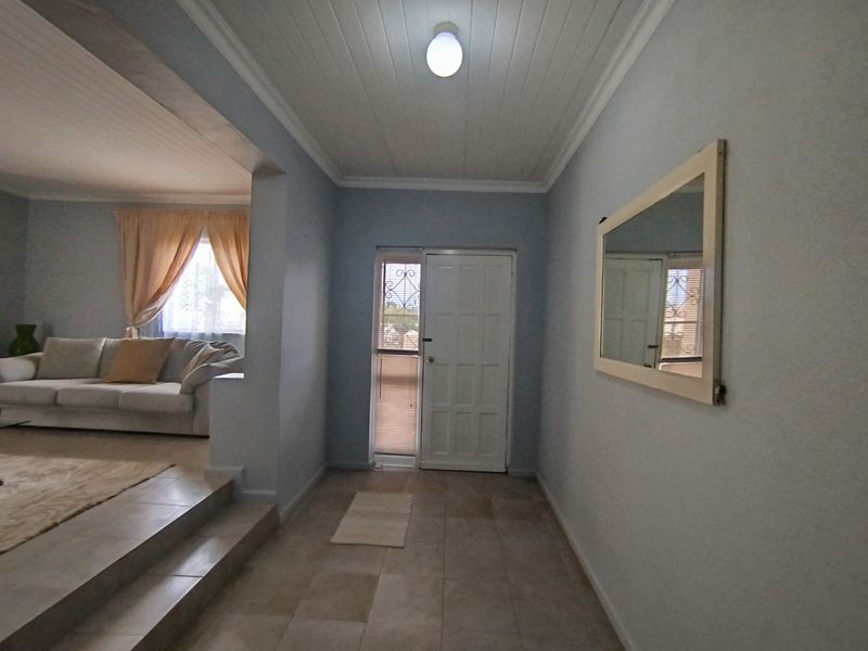 A bright entrance hall featuring tiled flooring and a timber panelled ceiling, providing a welcoming transition into the open-plan living area.
