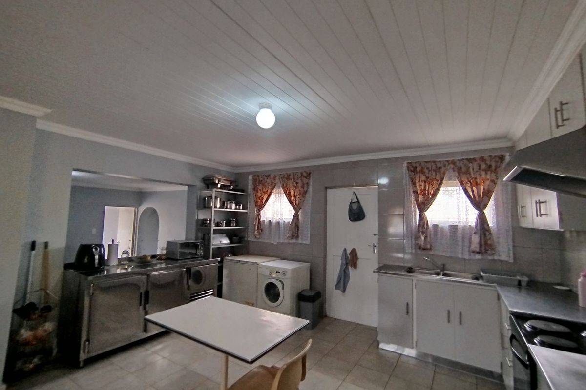 Functional kitchen featuring stainless steel countertops, built-in cabinetry, double basin sink, and an extractor fan with tiled flooring throughout.