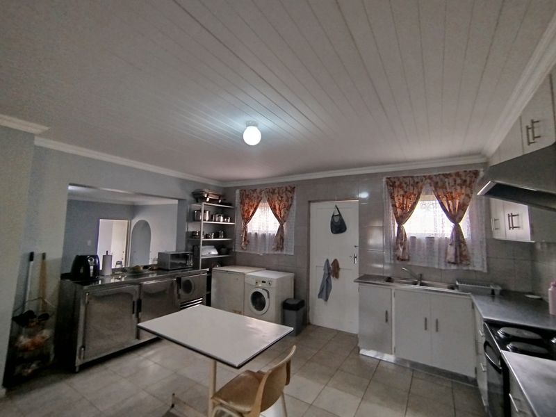 Functional kitchen featuring stainless steel countertops, built-in cabinetry, double basin sink, and an extractor fan with tiled flooring throughout.
