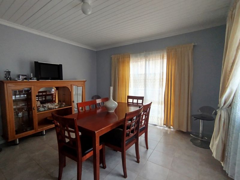 A dining room featuring tiled flooring, a sliding glass door providing natural light, and a tongue and groove ceiling.