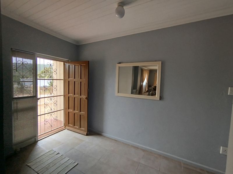 A clean, empty entry area featuring tiled flooring, a timber panel door, and a security gate leading to the exterior.