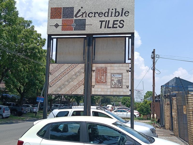 Street-facing commercial signage for an industrial property, featuring a prominent display board with tile samples and clear street address visibility.