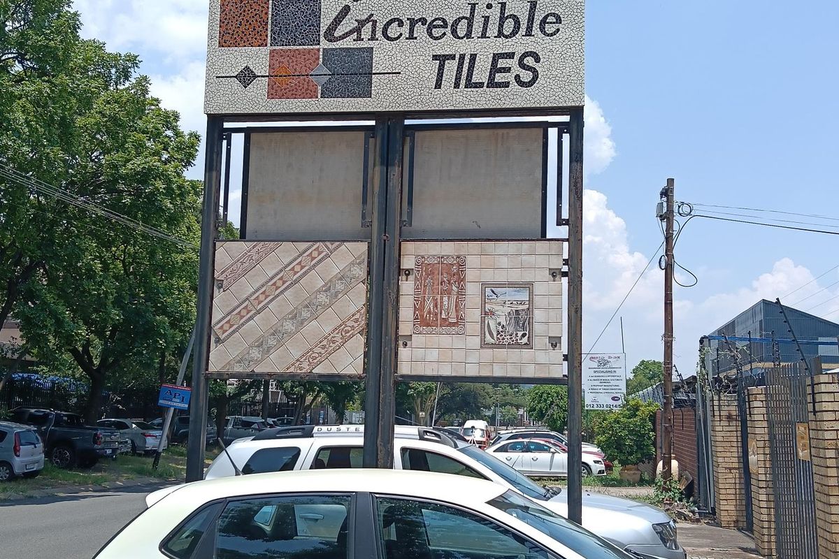 Street-facing commercial signage for an industrial property, featuring a prominent display board with tile samples and clear street address visibility.