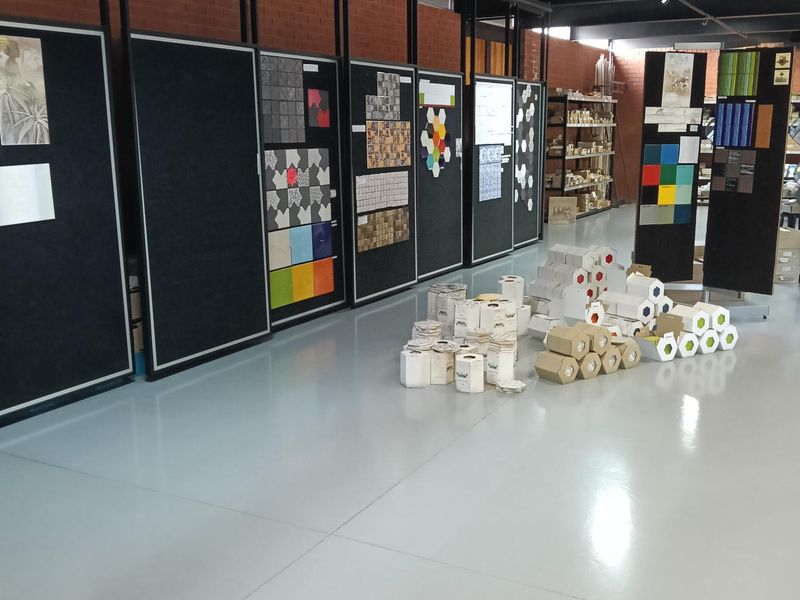 Spacious industrial showroom area featuring polished concrete flooring, exposed timber beam ceiling, and integrated display panels for product presentation.