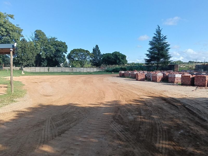 Expansive unpaved industrial yard area featuring a secure perimeter boundary wall and ample open space for storage or operational use.