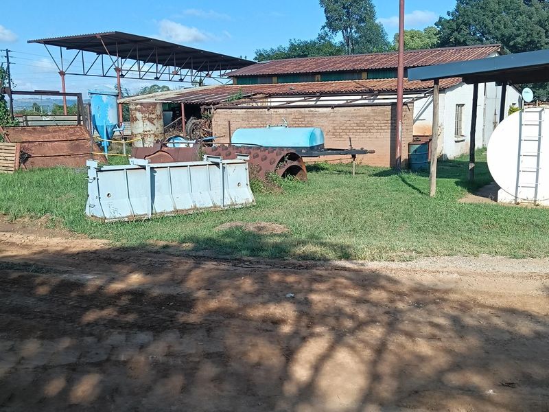 Rear exterior view of an industrial property featuring brick walling, metal roofing structures, and outdoor storage tanks on a grassed yard.