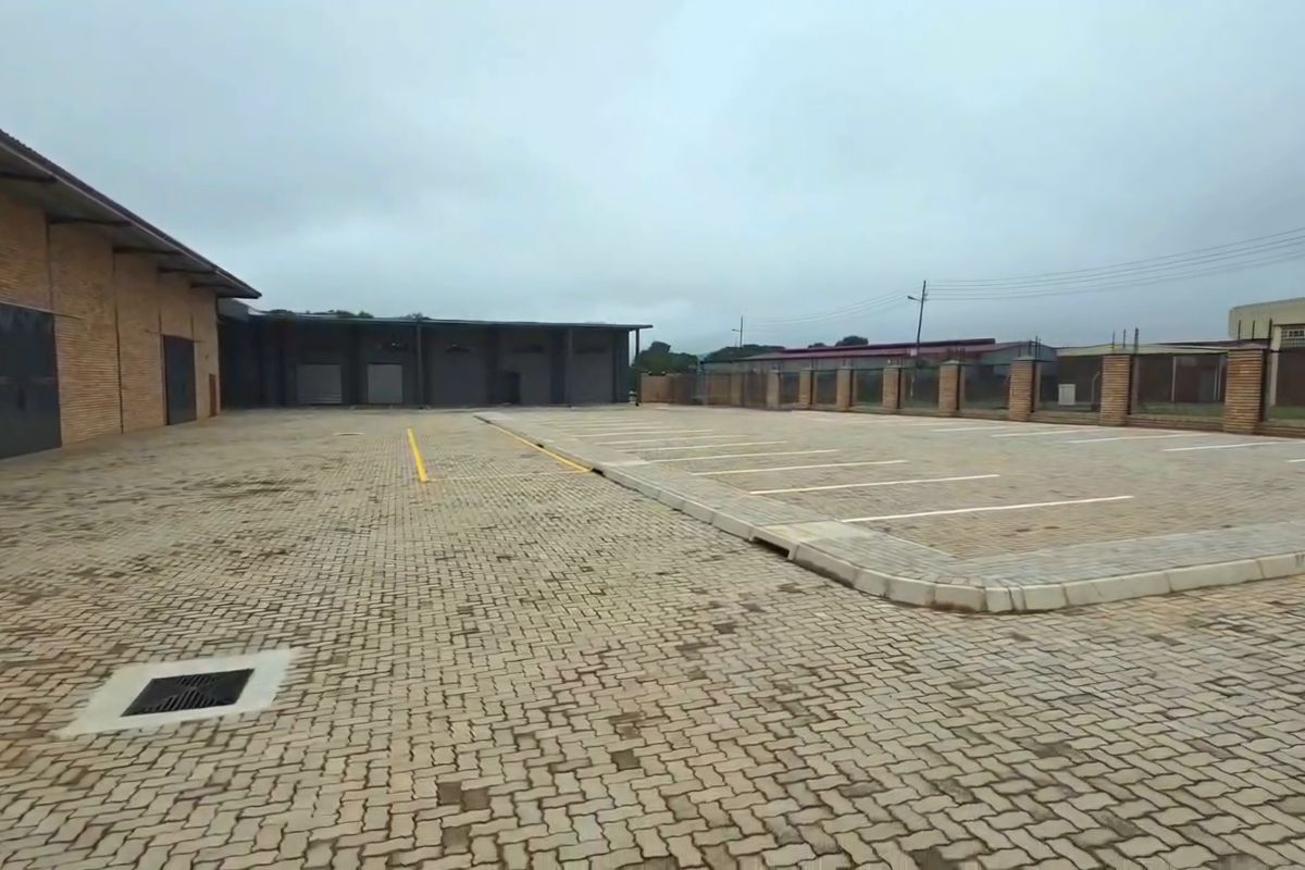 Spacious industrial paved yard featuring marked parking bays, brick building facade, and secure perimeter walling.