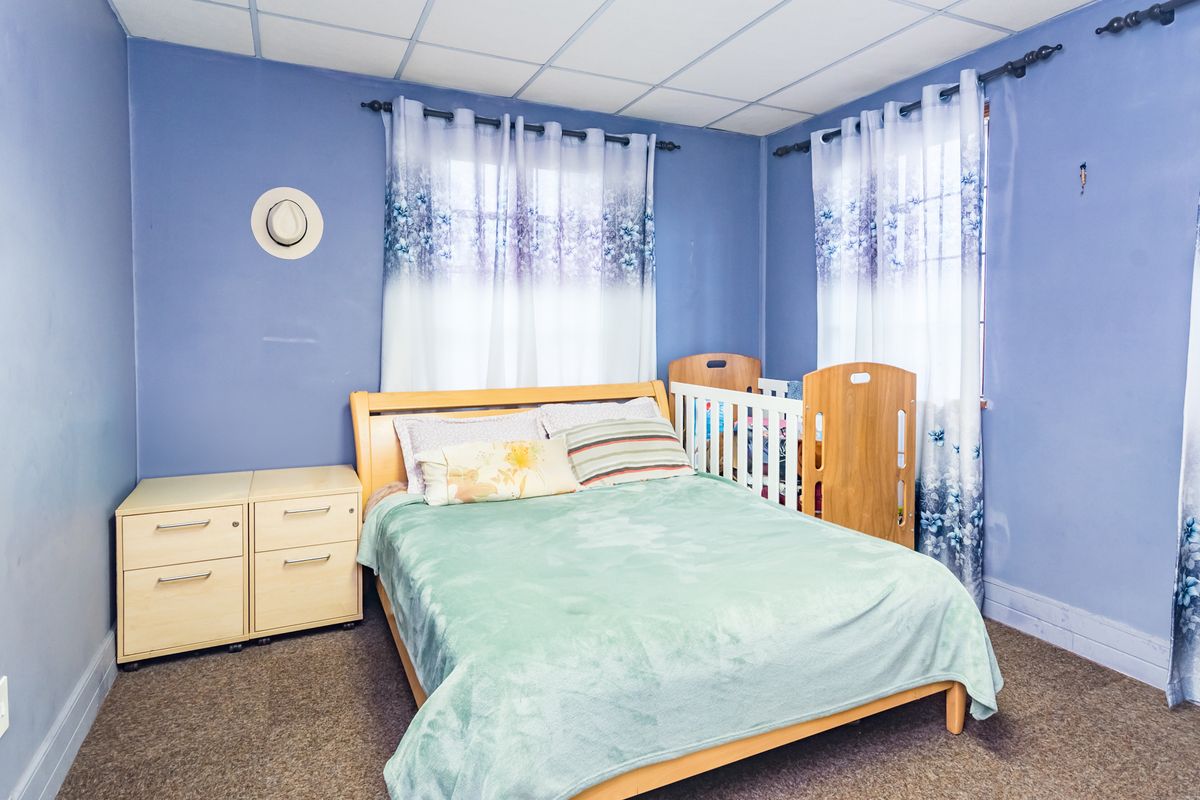 A bedroom featuring a drop ceiling and carpeted flooring, currently utilized as a sleeping space.