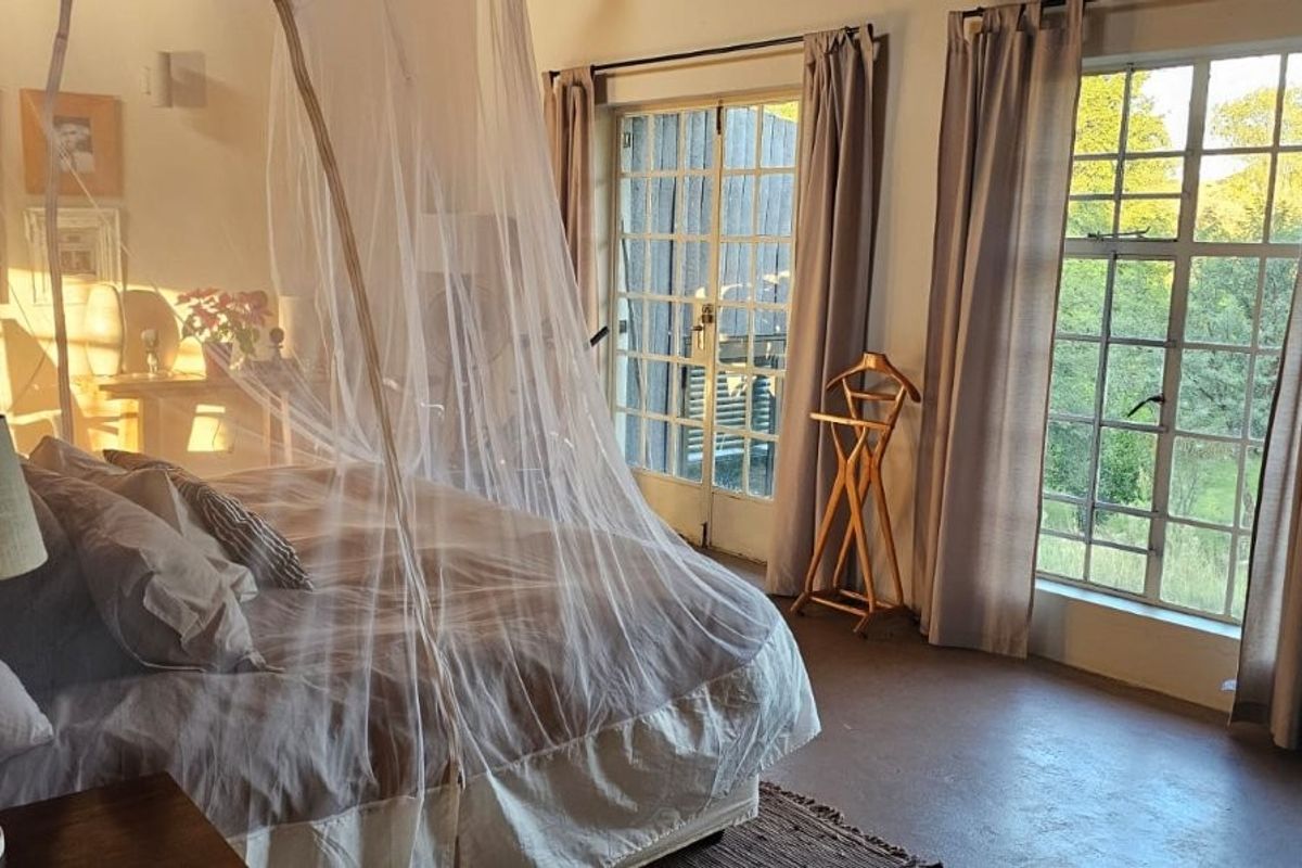 Spacious bedroom featuring large steel-framed windows, concrete flooring, and direct access to the outdoors through glass-paned french doors.