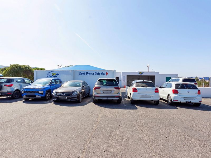 Exterior view of a commercial car wash facility with an asphalt parking area and dedicated service bays.