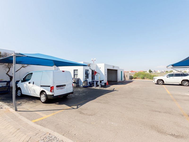 Exterior view of a commercial parking area featuring asphalt surfacing, marked bays, and protective shade sail structures for vehicles.