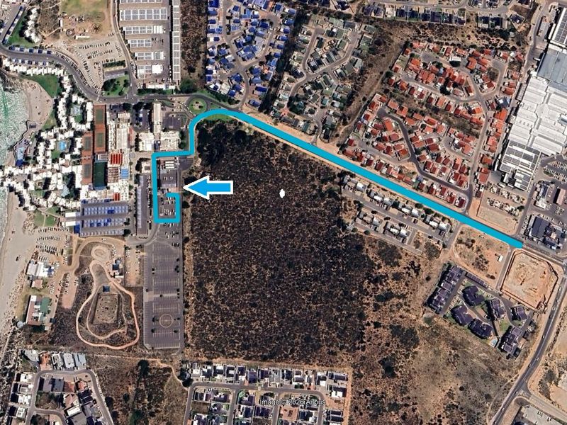 Aerial view showing the property location, surrounding road infrastructure, parking facilities, and proximity to the coastline and residential areas.