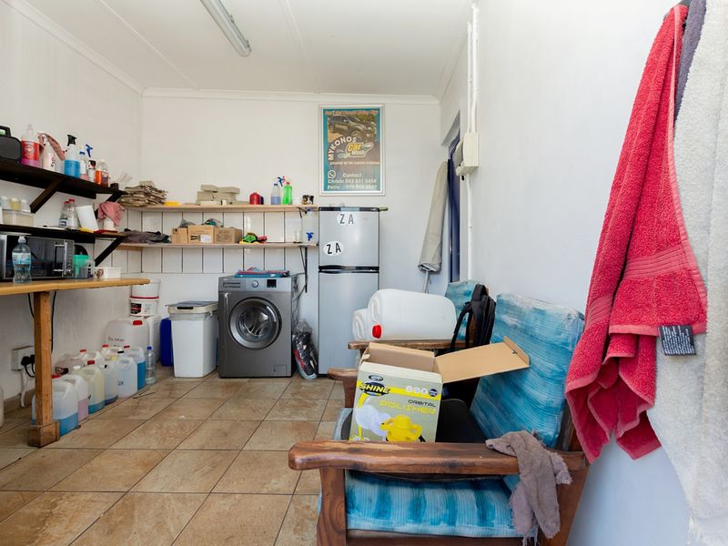 A functional laundry and utility space featuring tiled flooring and built-in shelving for storage.