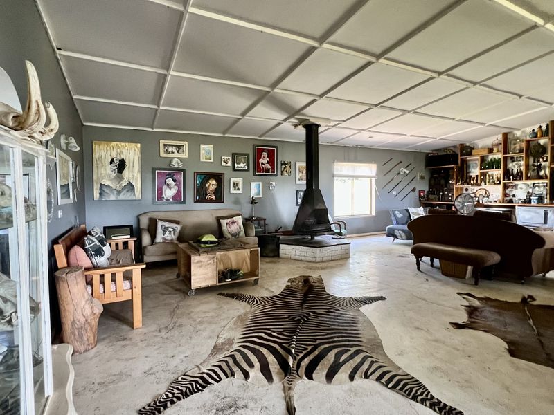 Spacious living area featuring a central freestanding fireplace, built-in shelving units, and a unique tiled ceiling design with concrete flooring.