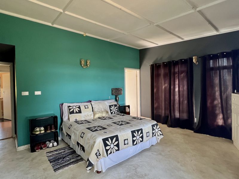 Spacious bedroom featuring tiled flooring, a panelled ceiling, and built-in cupboards, with direct access to an adjoining room.