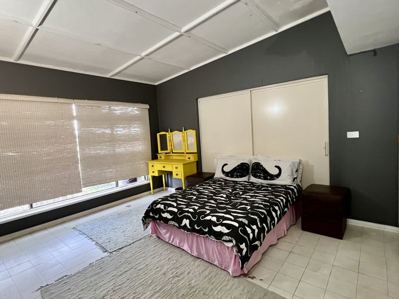 A bedroom featuring tiled flooring, built-in sliding door wardrobes, and a suspended ceiling. The room requires cosmetic updates to improve its overall condition.