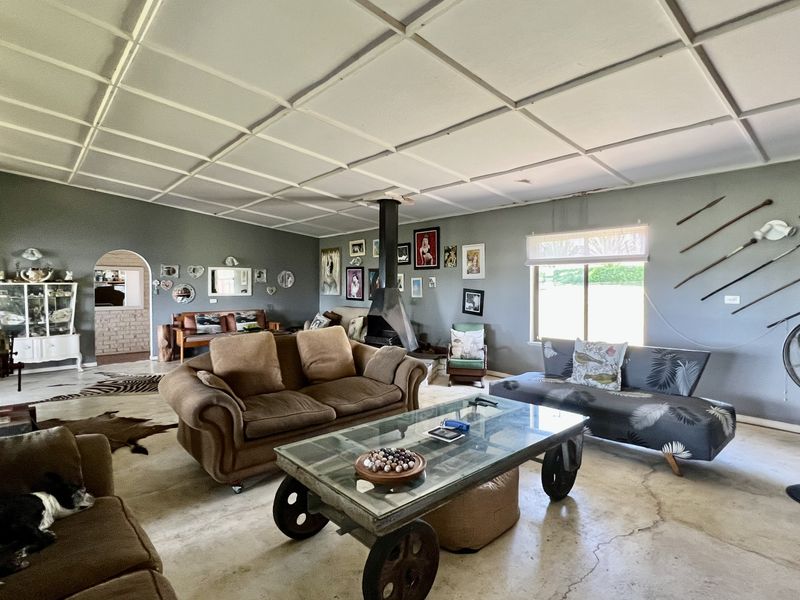 Spacious living room featuring a central freestanding fireplace, polished concrete floors, and an arched entryway leading to adjacent living areas.