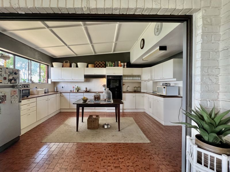 Spacious kitchen featuring white built-in cabinetry, integrated oven, extractor fan, and tiled flooring, offering a functional layout with ample counter space.